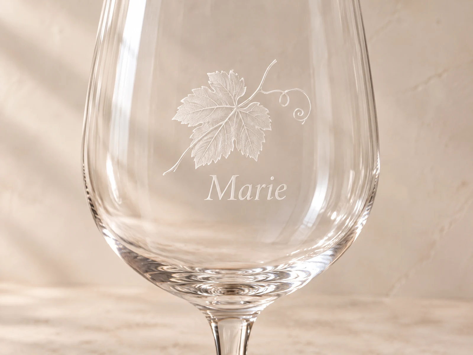 Nahaufnahme einer feinen Glasgravur mit Weinblatt und Namen