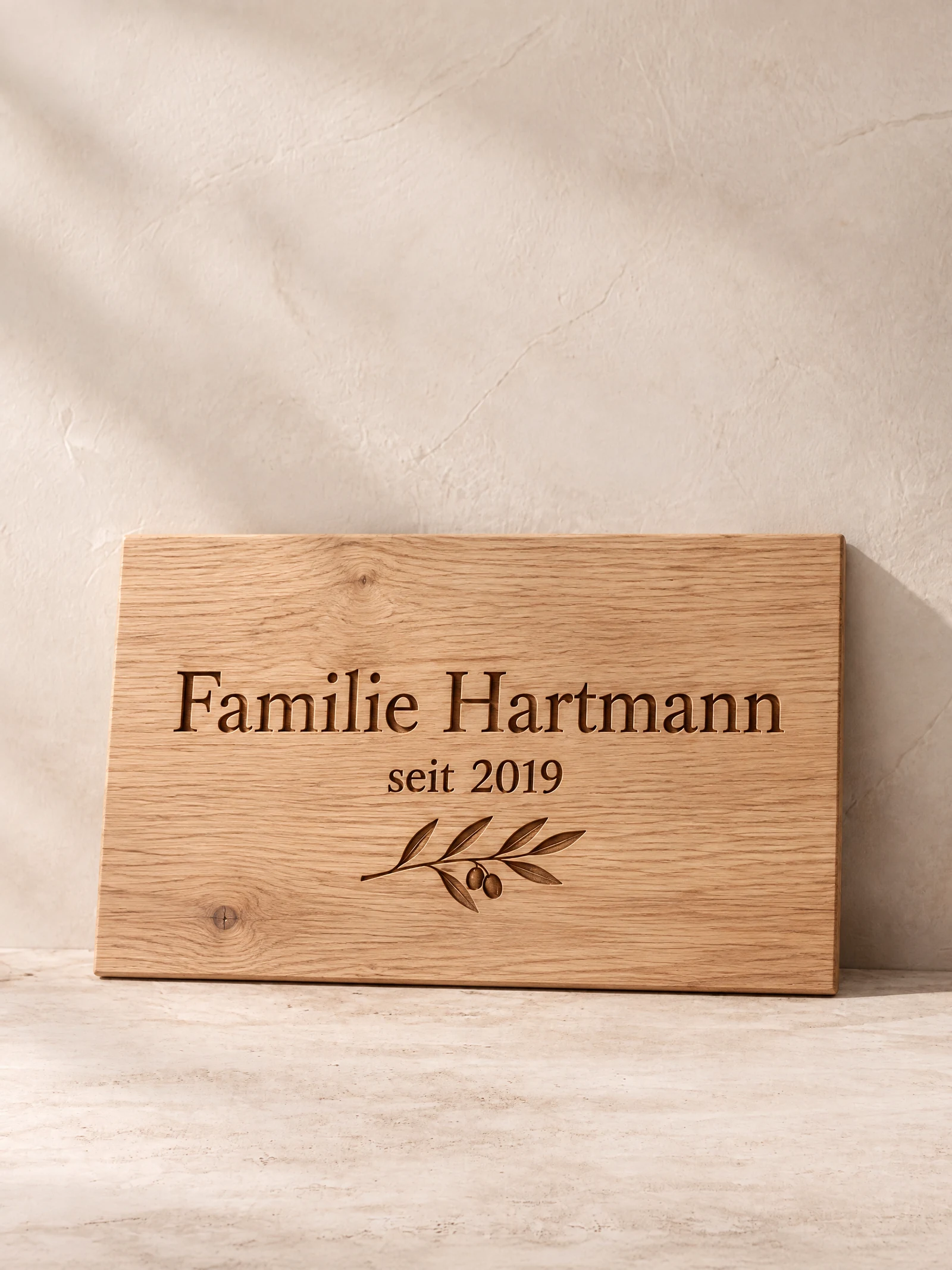 Eichenholzschild mit Lasergravur „Familie Hartmann, seit 2019“ an einer hellen Putzwand